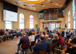 Image of the WTS Mulder Chapel with rows of individuals listening to a male speaker.